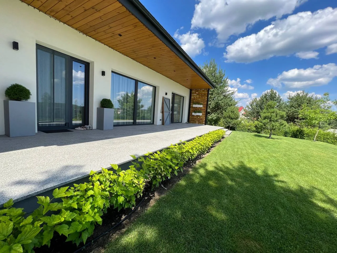 Modern single-storey passive-level house in Bucha with deep roof overhang, garden terrace and large glazed openings